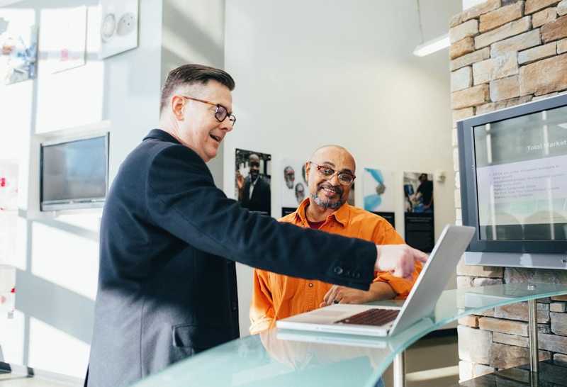 Two men discussing sales enablement technology in an office setting.